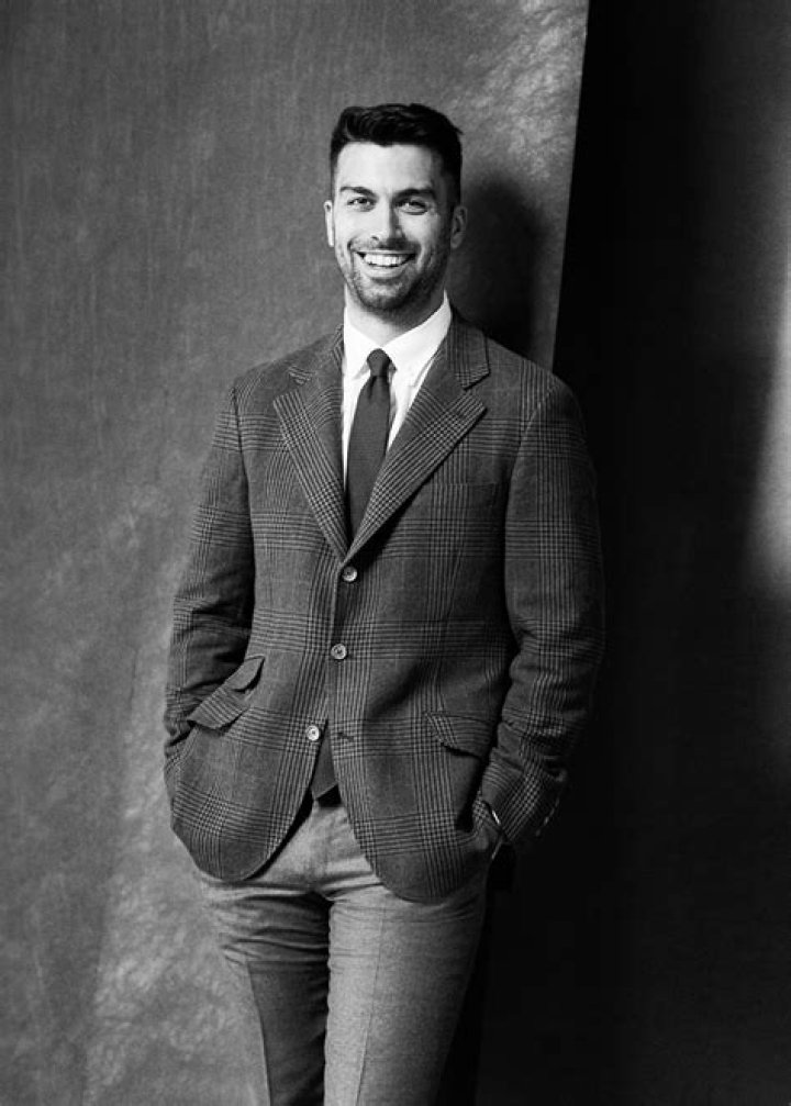 David Mumeni posing for a picture by wearing long green jacket and a black trouser.